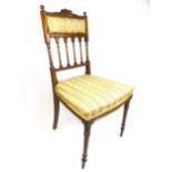 An Edwardian yew bedroom chair with beige striped floral upholstery on turned and carved front legs,