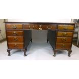 An early 20th century mahogany twin pedestal partners desk with tooled black surface over three