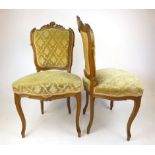 A pair of early 20th century French walnut rococo style bedroom chairs with green cut fabric