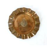 A copper trench art ashtray with pie crust edging and a central emblem of the Third Dragoon Guards,