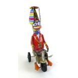 A tin plate wind up toy in the form of a duck riding a bike h.