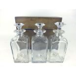 An early 19th century mahogany tantalus with three cut glass decanters and a Bramahs lock, h.