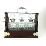 A modern reproduction mahogany and metalwares mounted tantalus containing three cut glass and
