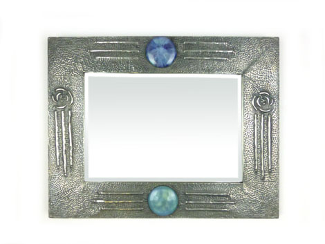 An Arts & Crafts mirror with an embossed white metal frame with Ruskin style plaques and beveled