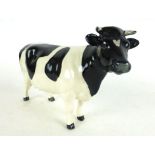 A Beswick ceramic figure modeled as a Friesian cow with black and white finish gloss, h. 11.