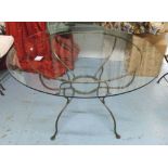 GARDEN TABLE, circular, with glass top on a rustic wrought iron base, 131cm diam x 76cm H.