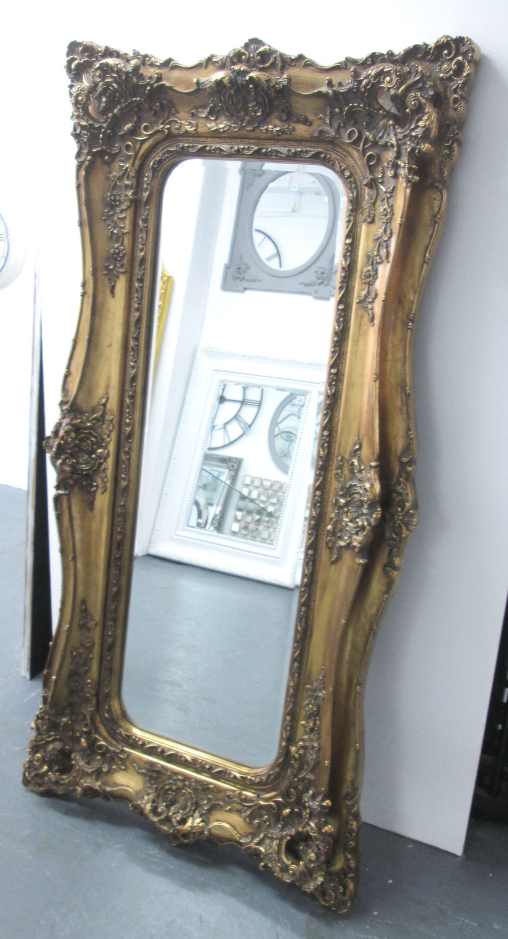 WALL MIRROR, gilt effect frame, with flowerhead and scroll decoration, and a bevelled plate,