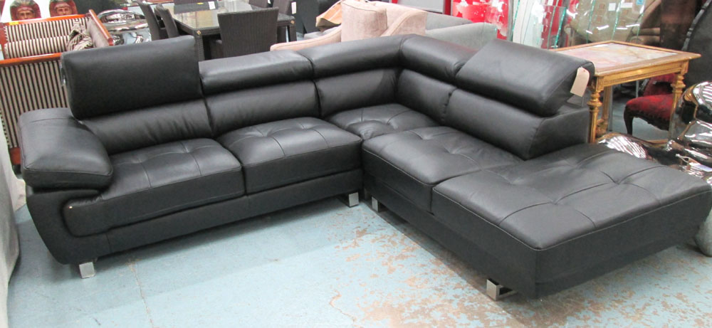 CORNER SOFA, in black leather with rising head rests on chromed metal supports, 261cm x 230cm.