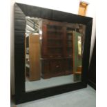 WALL MIRROR, of large proportions, with a black frame by J.N.L.