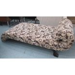 CHAISE LONGUE, of scrolling form, with a contemporary fabric of foliate design, on ebonised feet,