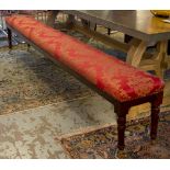 LONG STOOL, part Victorian walnut in red damask on brass castors (adapted) 259cm x 32cm.