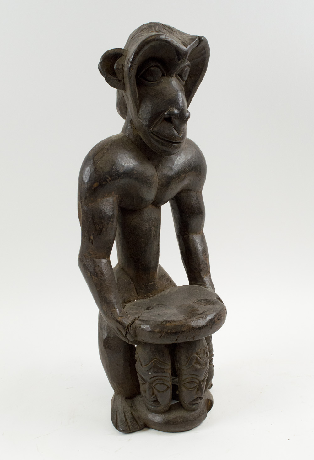 MONKEY FIGURAL CARVING, West African wood, depicting a monkey holding a stool in offetory pose,