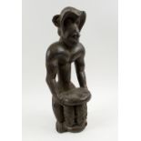 MONKEY FIGURAL CARVING, West African wood, depicting a monkey holding a stool in offetory pose,