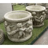 PLANTERS, a pair, in reconstituted stone of circular form with putti decoration.