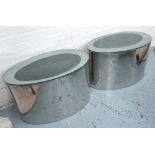 LOW TABLES, a pair, by Megaron, in the form of polished metal ovals with glass top,