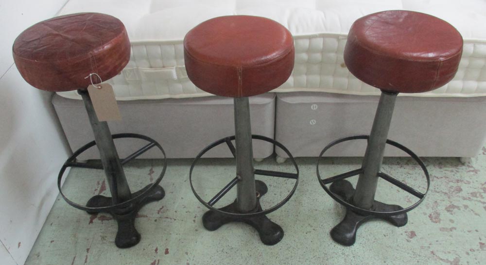 LEATHER TOPPED STOOLS, a set of three, 20th century, with metal construction and foot rings,