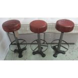 LEATHER TOPPED STOOLS, a set of three, 20th century, with metal construction and foot rings,