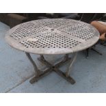 GARDEN TABLE, weathered teak circular on shaped supports, 130cm diam. x 75cm H.