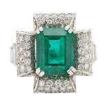 An emerald and diamond set cocktail ringclaw set with a trap cut emerald, the scrolling border