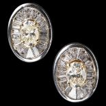 A pair of diamond set studs each claw set with a central oval yellow diamond, in a collet set border