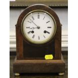 An Edwardian mahogany mantel clock, the arched case with brass bun feet, enamel dial, French