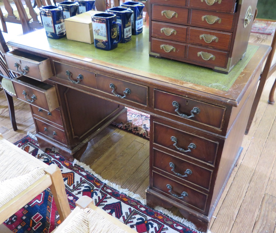 A mahogany veneered pedestal desk, the leather inset rectangular top over beaded drawers and bracket