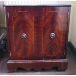 A mahogany veneered crossbanded T.V. cabinet, the rectangular top with serpentine front over a