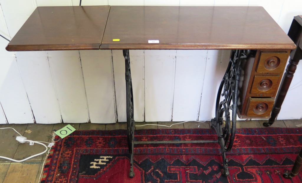 A mahogany and cast iron side table, formerly a Wilcox and Gibb sewing machine treadle with drop