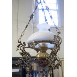 A brass ceiling light, in the form of an oil lamp with white glass dome and acanthus cast