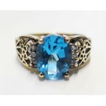 A 14 carat gold ring set with a central blue stone (possibly a zircon) with diamond shoulders