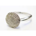 A round diamond cluster ring comprising pave set diamonds in 18 carat white gold