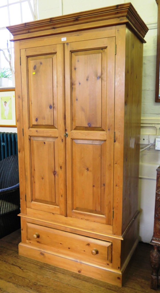 A pine wardrobe, with panelled doors over a frieze drawer and plinth base, 102cm wide