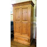 A pine wardrobe, with panelled doors over a frieze drawer and plinth base, 102cm wide