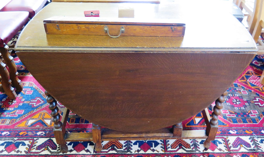 An oak gateleg table, the oval top on barley twist and block legs joined by stretchers, 106cm, and