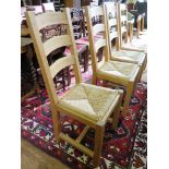 A set of four modern oak dining chairs, the ladder backs over rush seats on chamfered square legs (