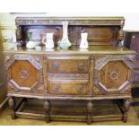 A 1920's oak sideboard, the grape and vine carved top rail over a panelled back on stop fluted cup