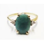 A gold colour metal ring set with an oval emerald, with diamond set shoulders