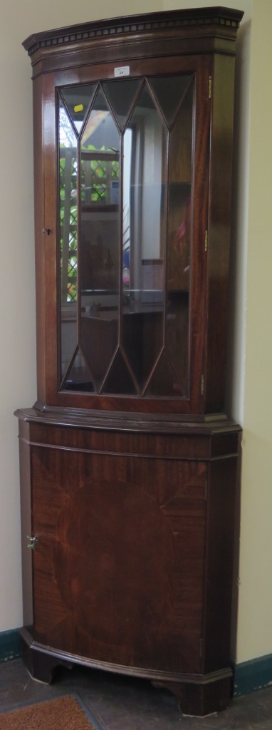 A mahogany corner cabinet, the dentil cornice over a glazed door and oval veneered panel door on