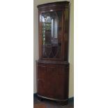 A mahogany corner cabinet, the dentil cornice over a glazed door and oval veneered panel door on