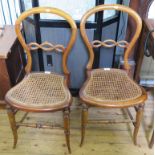 A pair of Victorian birch wood balloon back bedroom chairs with interlaced rails and cane seats on