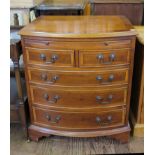 A yew wood crossbanded veneered bowfront chest of drawers, with brush slide, two short and three