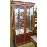 A yewwood veneered display cabinet, the cut glass pair of doors enclosing a mirrored interior