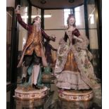 A pair of German porcelain figures dancing, wearing a purple coat and purple lace dress, the lady