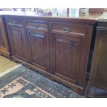 An Edwardian walnut sideboard, with three frieze drawers above three panelled doors carved with