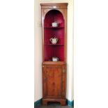 A yewwood veneer corner cabinet, the shaped open shelves above a panelled door on bracket feet, 40cm