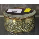 An attractive oval shaped brass cased trinket box with putti scenes and bevelled glass lid