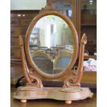 A Victorian mahogany toilet mirror, the oval plate on foliate stands and shaped base with two