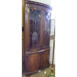 A George III style mahogany corner cabinet, with blind pendant cornice over a pair of glazed doors