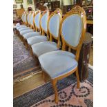 A set of eight stained beech dining chairs, with blue upholstery, the scroll carved oval backs on