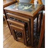 A nest of Chinese tables, the lacquered tops decorated with figures in relief, 51cm wide